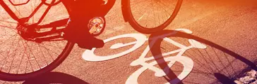 Shadow of cyclist riding a bike on bicycle lane through city street