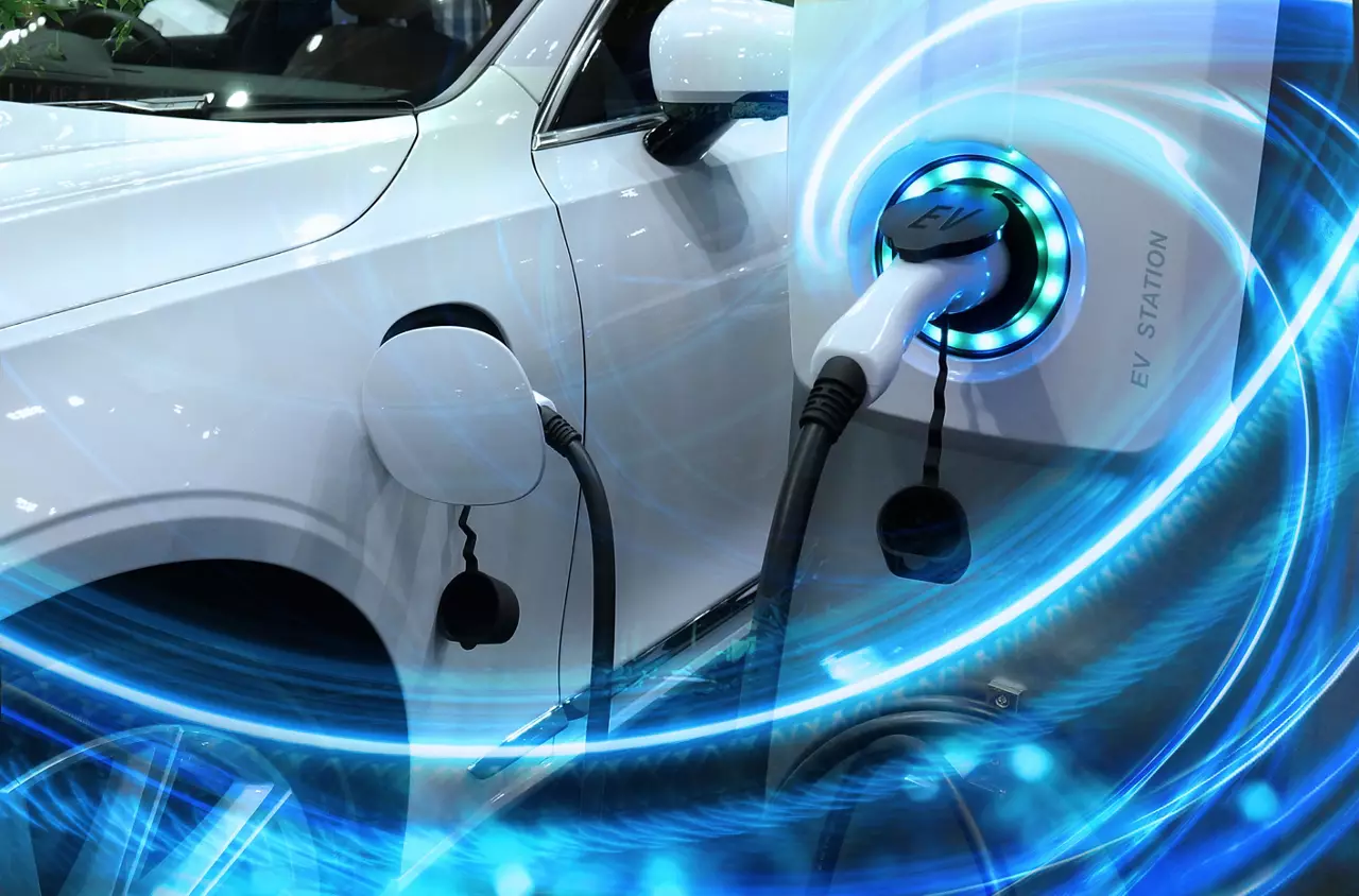 White electric vehicle at charging station with the power cable plugged in