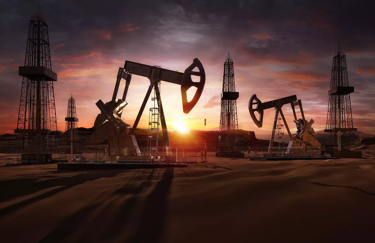 Oil pumps, drilling derricks from oil field silhouette at sunset