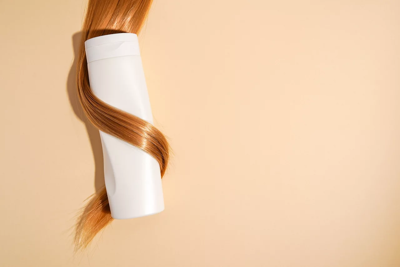 Blondes Haar gelockt um Shampoo-Flasche Nahaufnahme auf hellem Hintergrund, Kopie Raum
